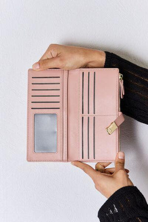 a person holding a pink wallet in their hand