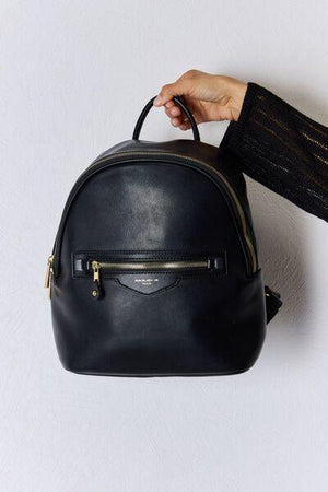 a hand holding a black leather backpack