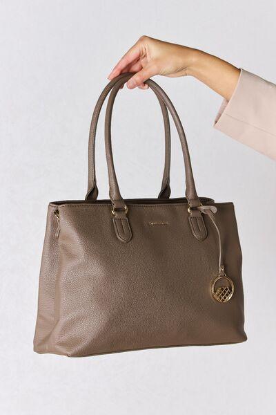 a woman's hand holding a brown purse