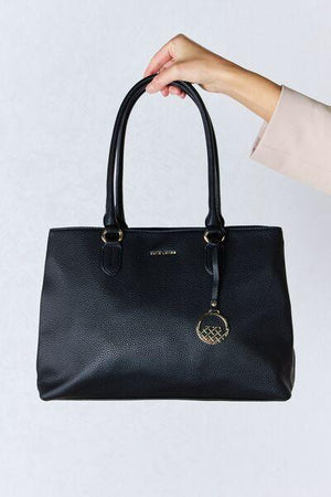 a person holding a black handbag in their left hand