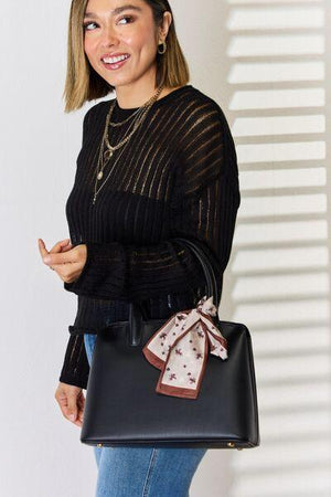 a woman holding a black purse with a bow on it