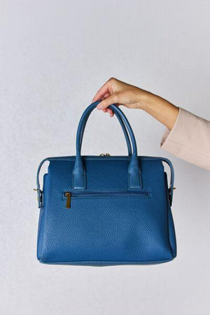 a person holding a blue handbag in their left hand