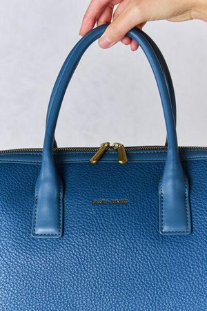 a person holding a blue handbag in their left hand