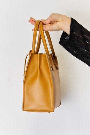 a hand holding a tan and tan purse