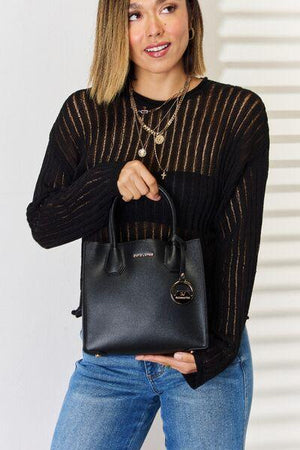 a woman holding a black handbag in her right hand