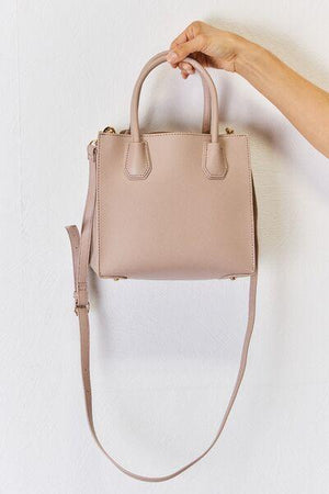 a hand holding a pink purse on a white wall