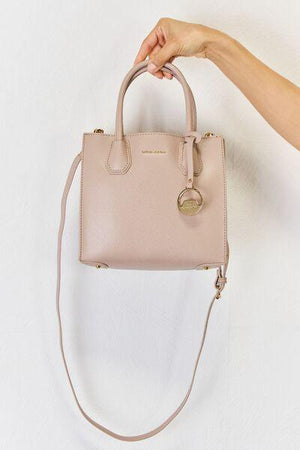 a hand holding a pink purse on a white background