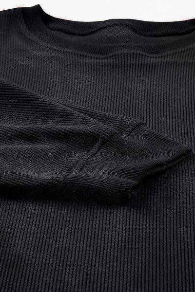 a black t - shirt that is folded on a white surface