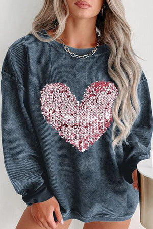 a woman wearing a blue sweater with a sequin heart on it