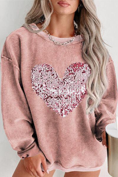 a woman wearing a pink sweater with a sequin heart on it