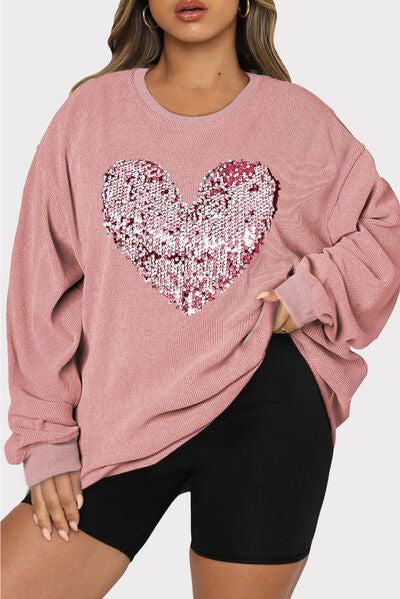 a woman wearing a pink sweater with sequin heart