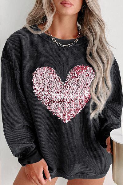 a woman wearing a black sweater with a heart on it