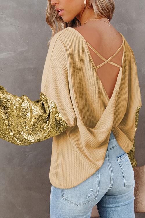 a woman wearing a gold sweater and jeans