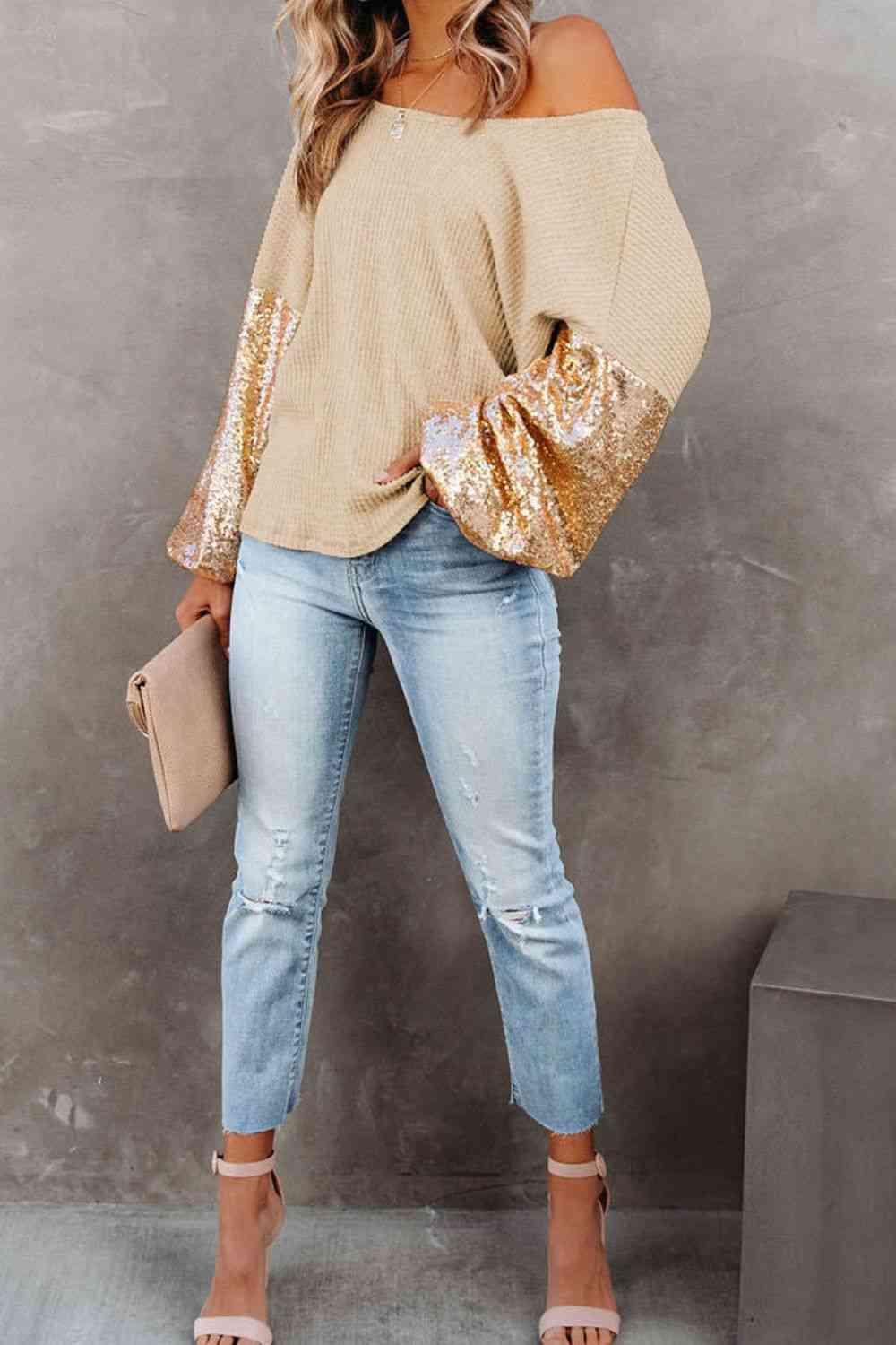 a woman wearing a gold sequin sweater and jeans