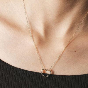 a woman wearing a necklace with a heart on it