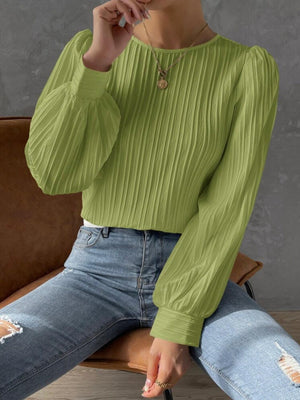 a woman sitting on a chair wearing a green sweater