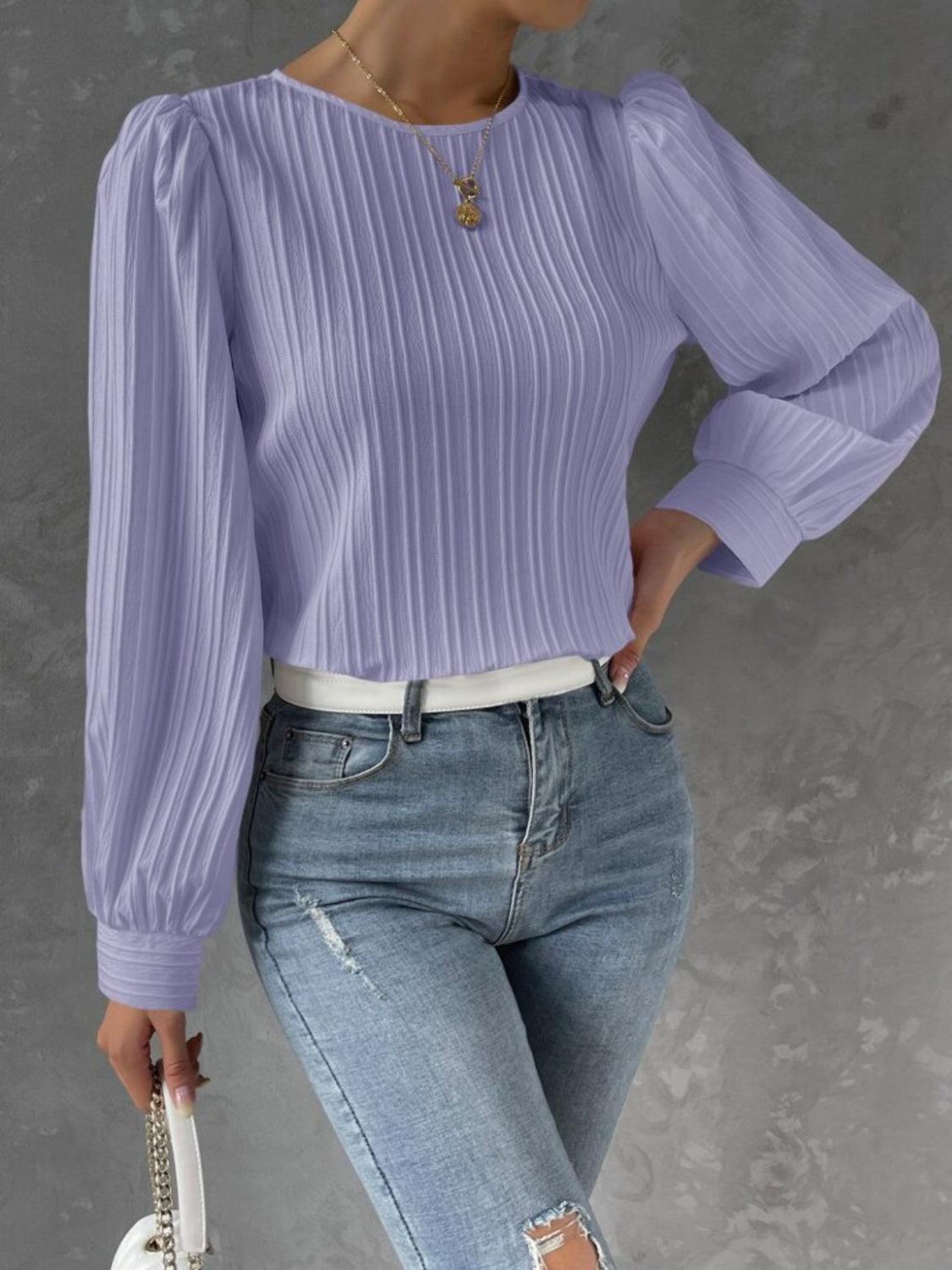 a woman wearing a purple top and ripped jeans