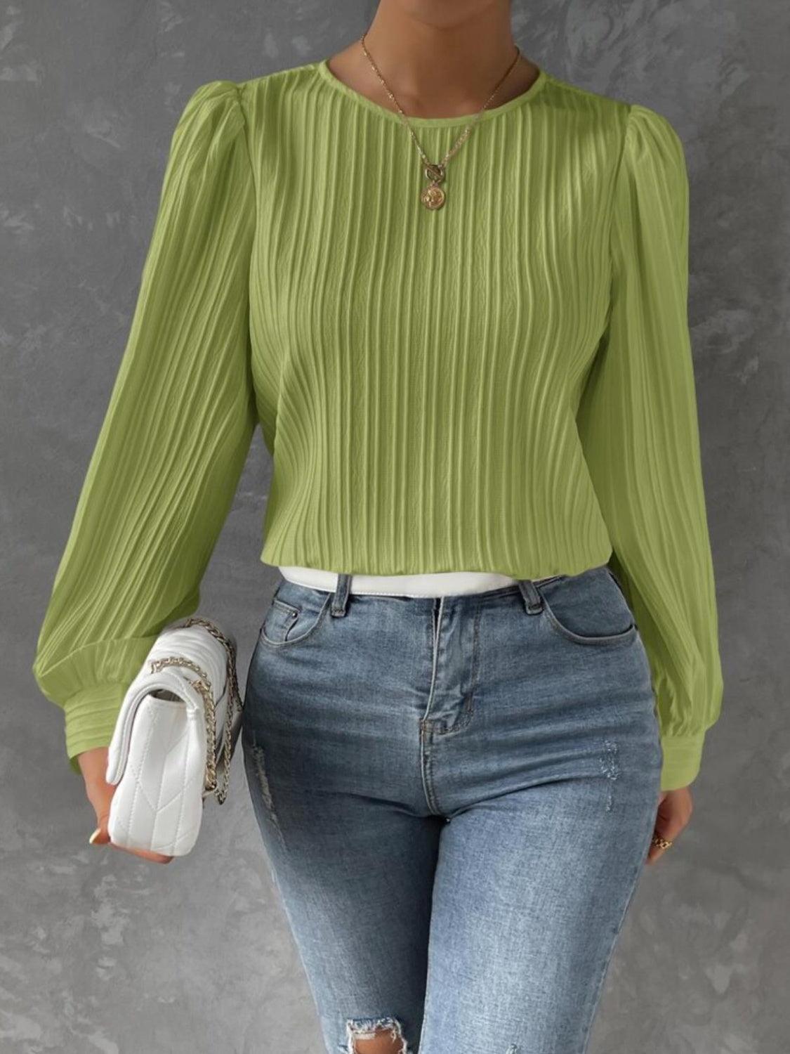 a woman wearing a green top and ripped jeans