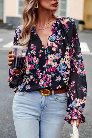 a woman in a floral shirt and jeans holding a drink