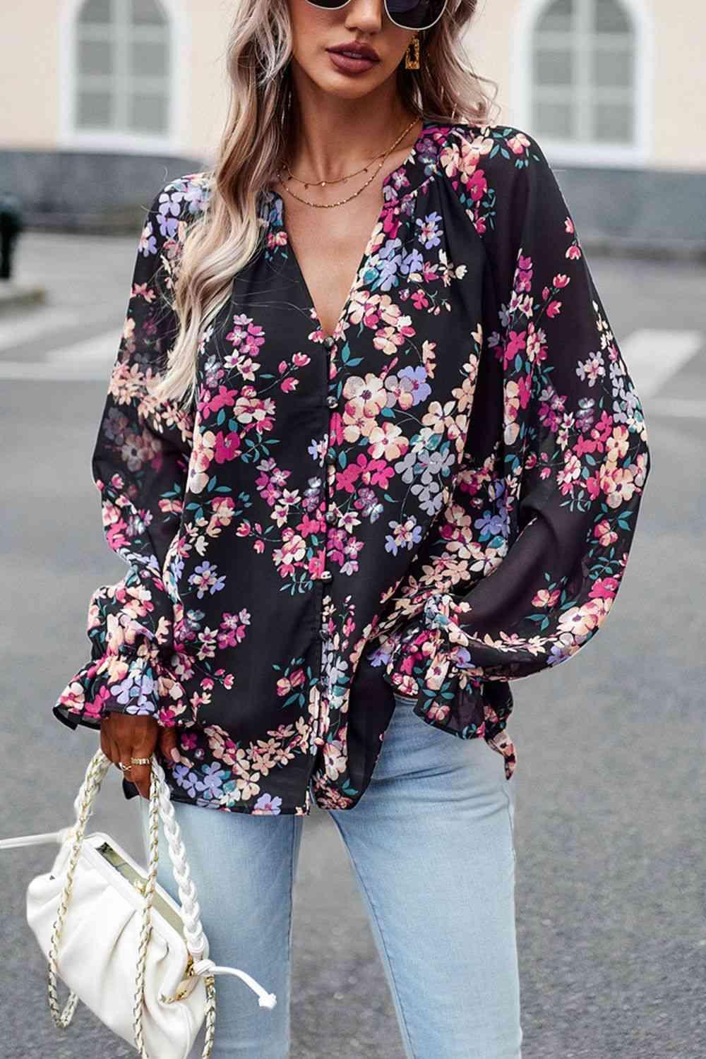 a woman wearing a black floral blouse and jeans