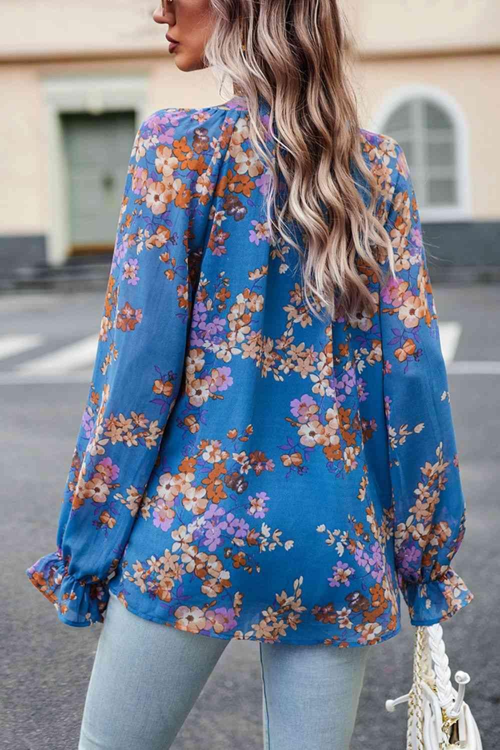 a woman wearing a blue floral blouse and jeans