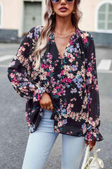 a woman wearing a black floral blouse and jeans