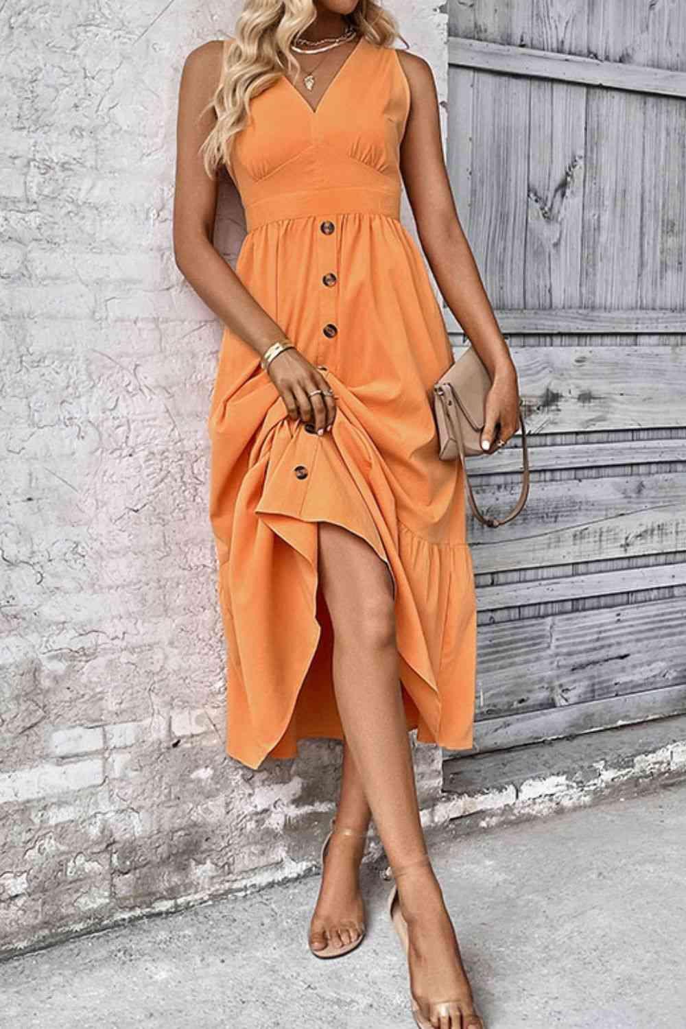 a woman in an orange dress leaning against a wall