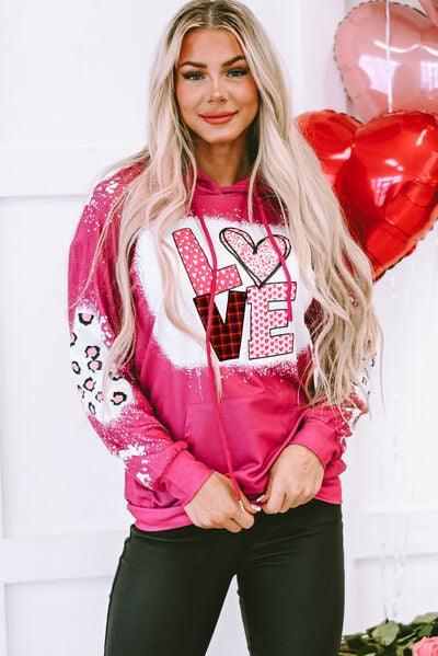 a woman with long blonde hair wearing a pink hoodie
