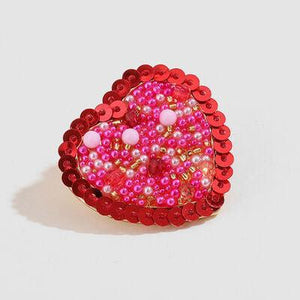 a heart shaped brooch with pink and red sequins