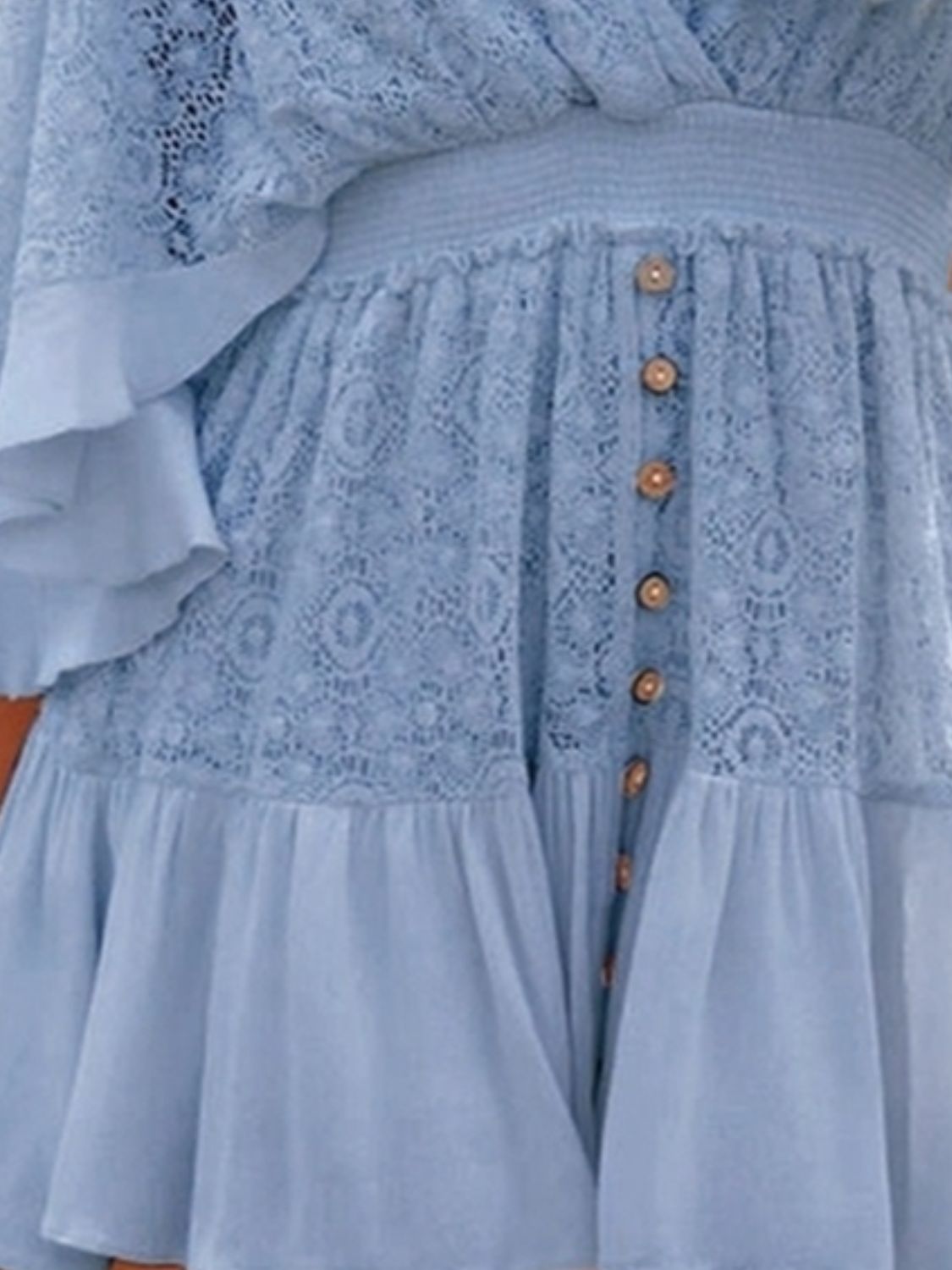 a woman wearing a blue dress with ruffled sleeves