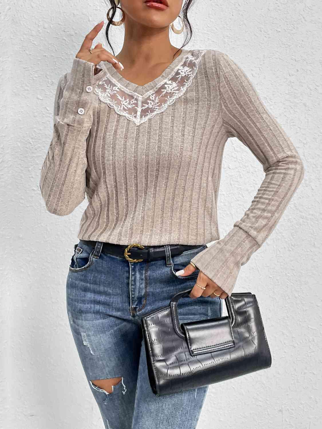 a woman in ripped jeans and a sweater holding a black purse