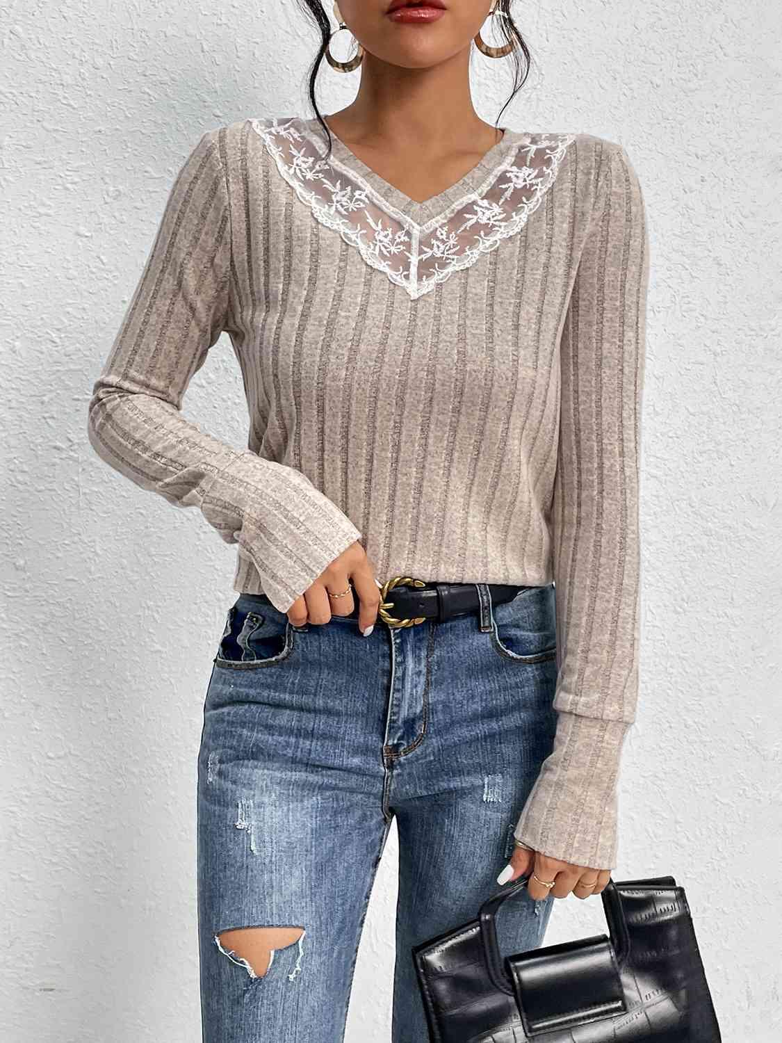 a woman in ripped jeans and a sweater holding a black purse