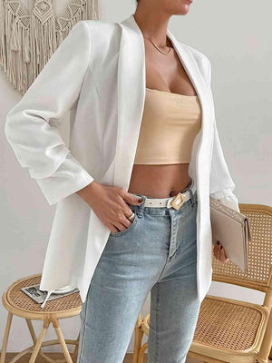 a woman wearing a white blazer and jeans