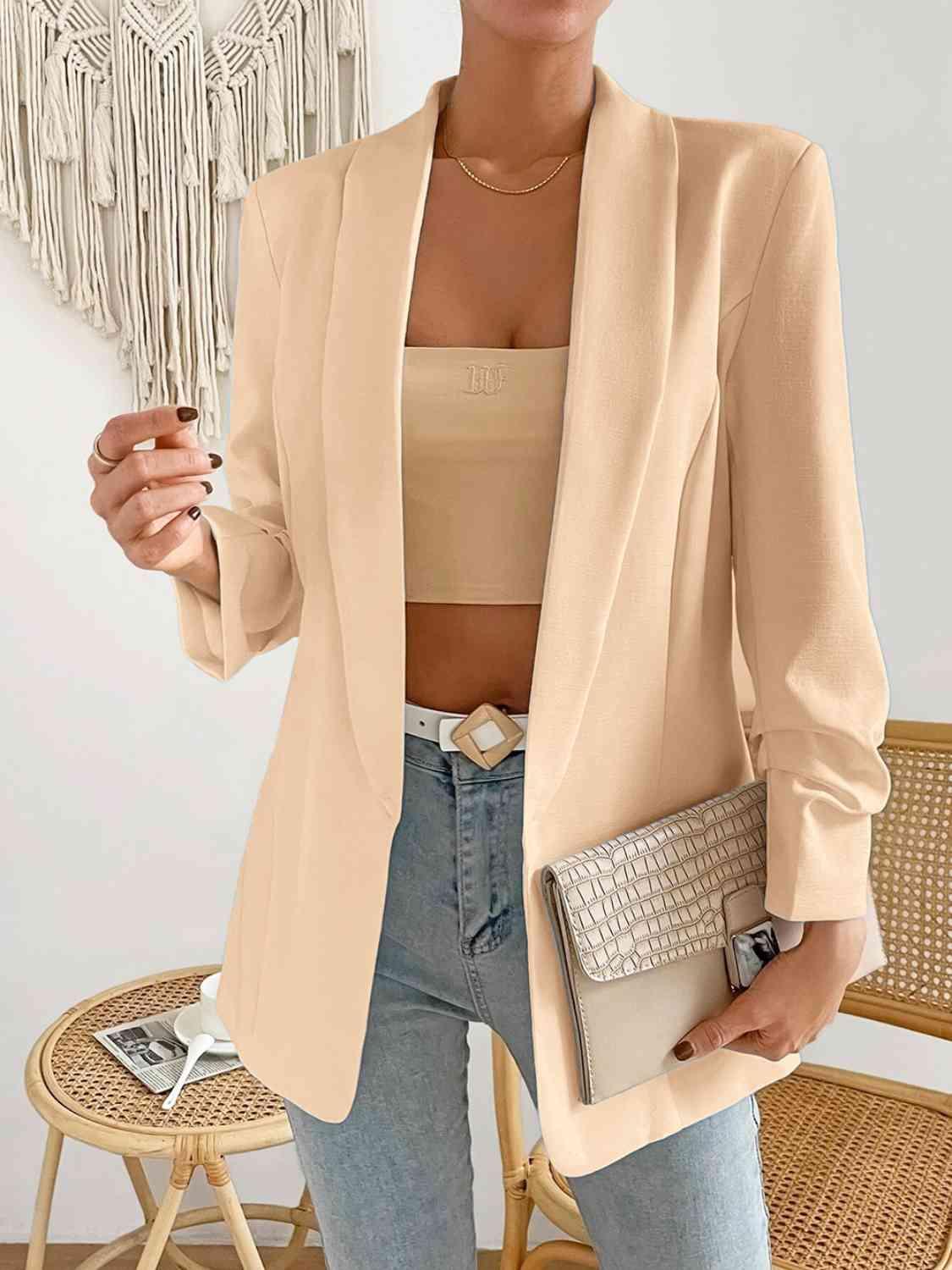 a woman wearing a beige blazer and jeans