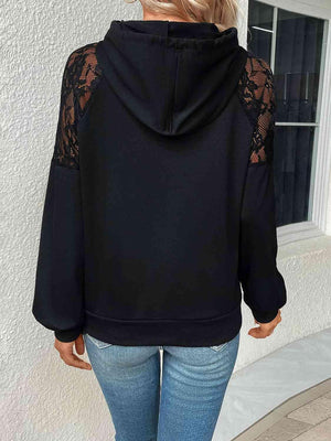 a woman wearing a black hoodie with lace sleeves