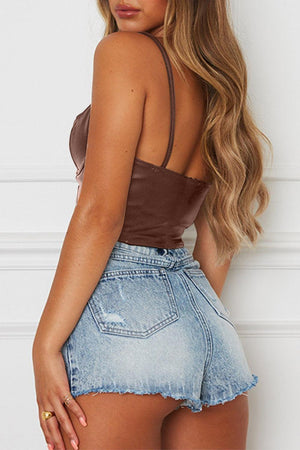 a woman wearing a brown top and denim shorts