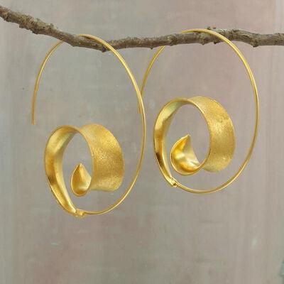 a pair of gold earrings hanging from a tree branch