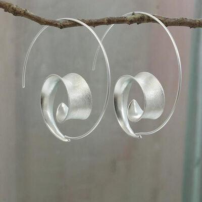 a pair of silver earrings hanging from a tree branch