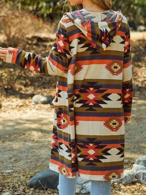 a woman standing in the woods wearing a colorful coat