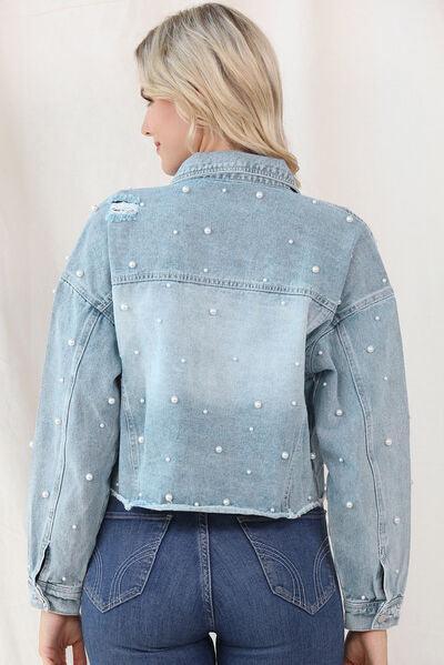 a woman wearing a jean jacket with pearls on it