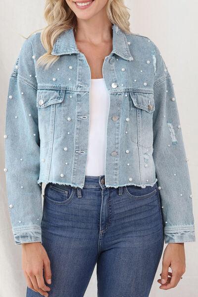 a woman wearing a denim jacket with pearls on it