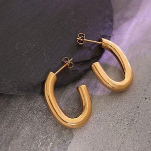 a pair of gold hoop earrings sitting on top of a rock