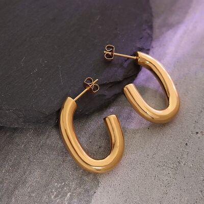 a pair of gold hoop earrings sitting on top of a rock