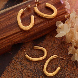 a pair of gold hoop earrings sitting on top of a wooden table