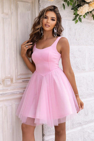 a woman in a pink dress leaning against a wall