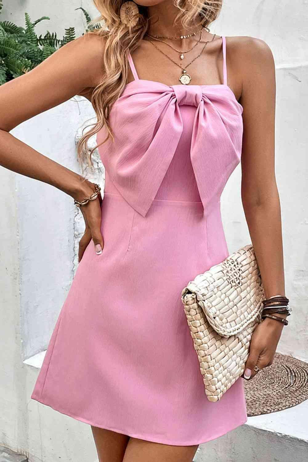 a woman wearing a pink dress with a bow at the neck