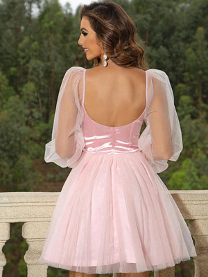 a woman in a short pink dress standing on a balcony