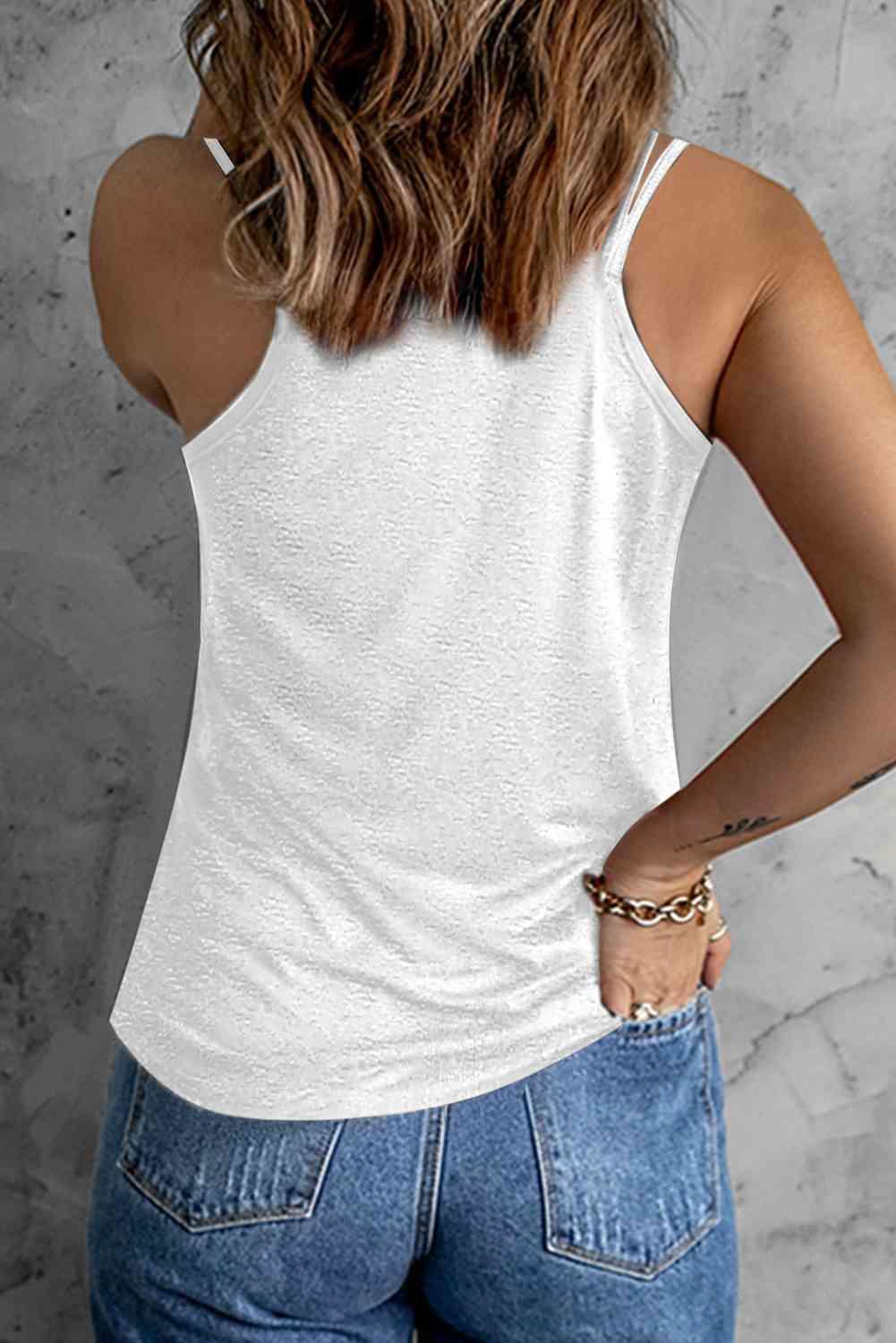 a woman wearing a white tank top and jeans