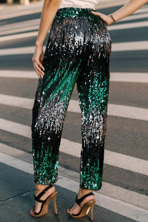 a woman standing on the side of a road wearing green and black sequin pants