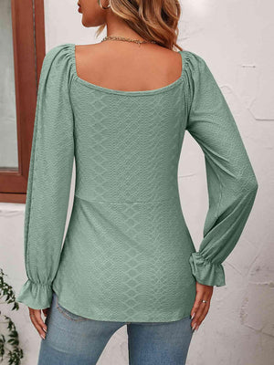 a woman wearing a green top with long sleeves